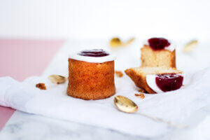 Kaksi Runebergintorttua, joista toinen on halkaistu. Edessä pikkulusikka.